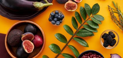Top view of colorful fruits and vegetables on a vibrant orange background, perfect for healthy lifestyle concepts.