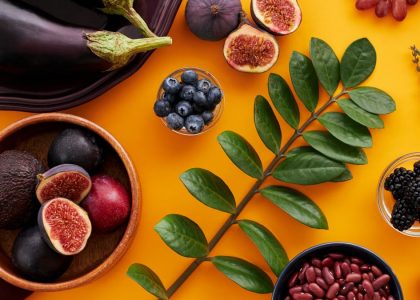 Top view of colorful fruits and vegetables on a vibrant orange background, perfect for healthy lifestyle concepts.
